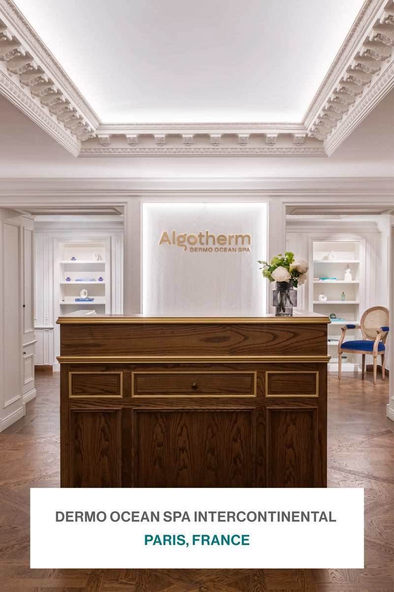 Reception area of Algotherm Dermo Ocean Spa Intercontinental in Paris, France, showcasing a classic wooden desk and elegant white interior.